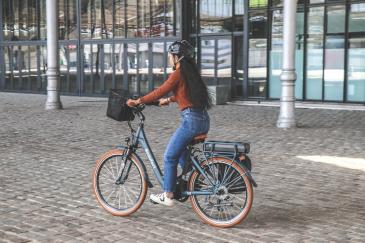 Een fietsende vrouw op een e-bike met een helm op