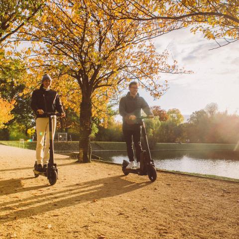 Twee personen op elektrische stepjes in een park