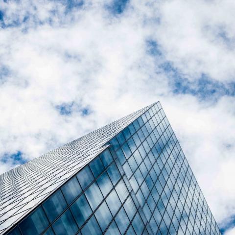 Hoog glazen kantoorgebouw met wolkenlucht